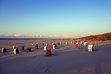 Juist-Töwerland: Eindrucksvoll wirft die untergehende Sonne vor der Dunkelheit noch lange Schatten auf dem Strand.