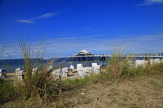 Timmendorfer Strand: Mondänes Seebad mit gemütlichen Charme. Der typische Blick von der Strandpromenade. Dünengräser, Strandkörbe und die Seebrücke mit Teehaus.