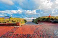 Wangerooge: Das rote Backsteinpflaster auf der Strandpromenade leuchtet im Sonnenaufgang.